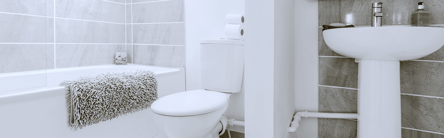  Clean bathroom interior with a toilet, sink, and bathtub.